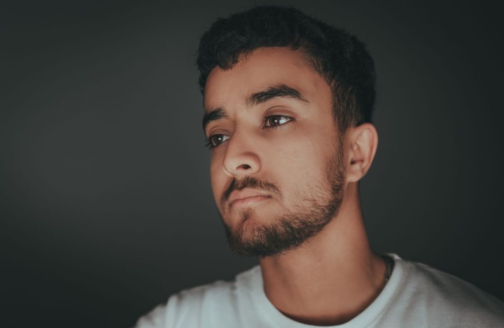 Portrait of a young man with a beard looking thoughtful in a studio setting.